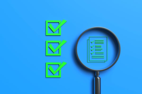 Magnifying glass examining electronic document icon symbolizes online approval, the paperless and a quality assurance inspection. Three other document icons are placed to the right of the magnifying glass.