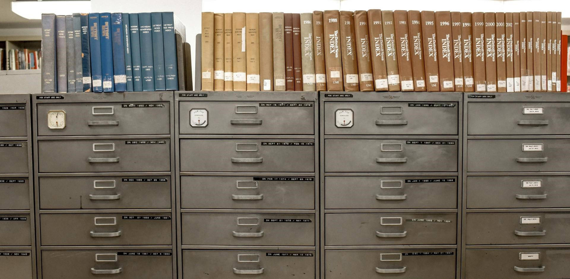 Metal file cabinets with indexed documents stored in notebooks are line up on top of the file cabinets represent the old-fashioned paper-based way to organize business information