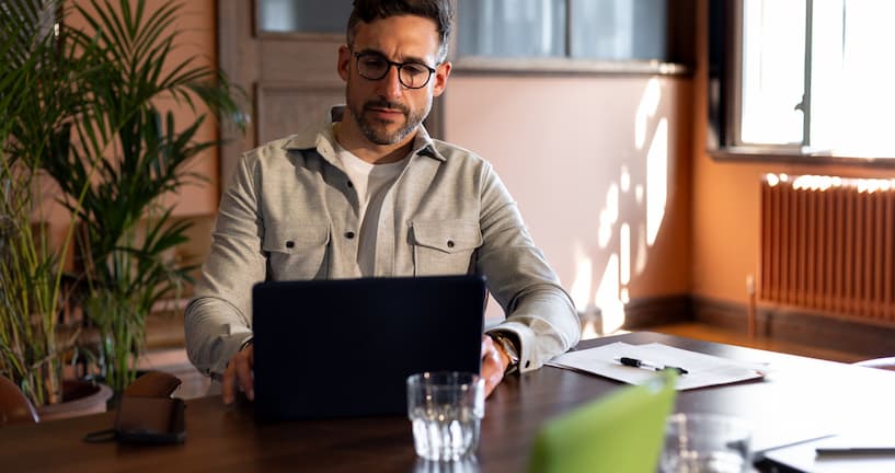 Mann sitzt am Schreibtisch vor seinem Laptop