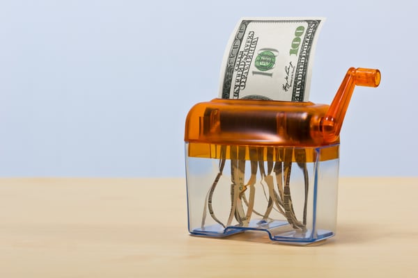 Photograph of paper money going through a paper shredder