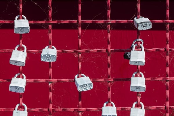 Locks on a red wire fence represent the security concept