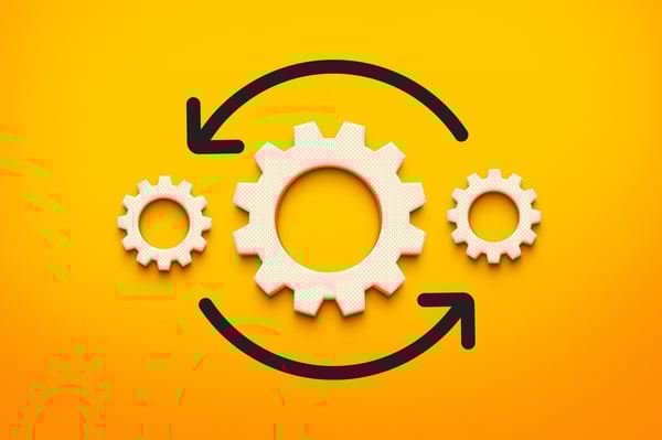 Three light tan gears on an orange background with a black arrow underneath them