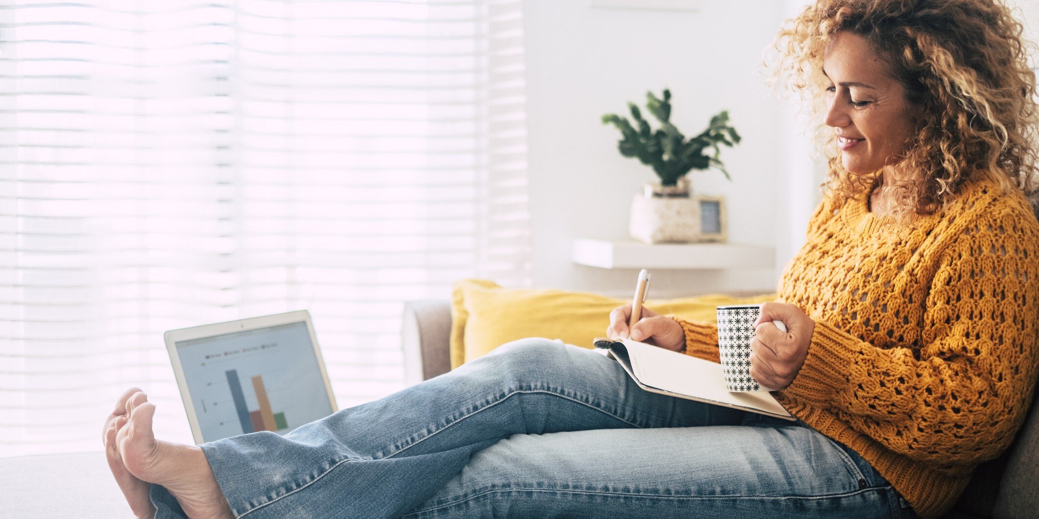 Woman working at home reclining on a couch wearing blue jeans